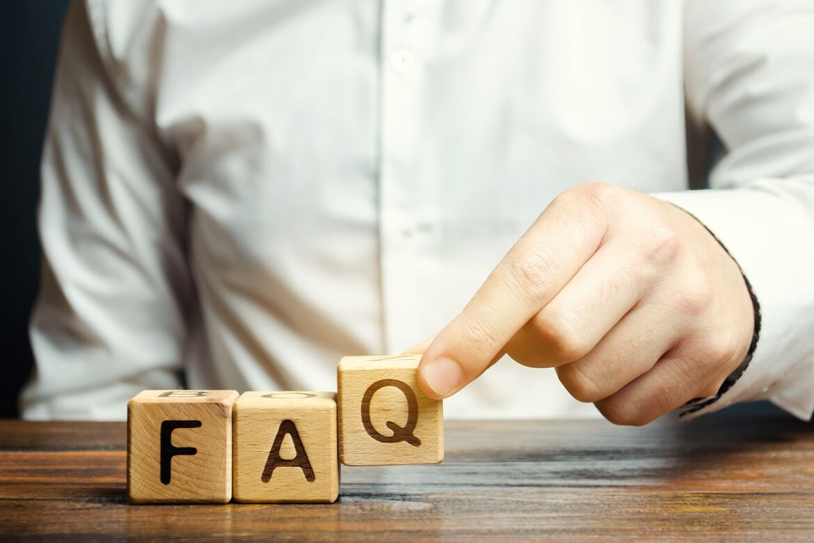 male employee uses wooden blocks to form the word "faq"