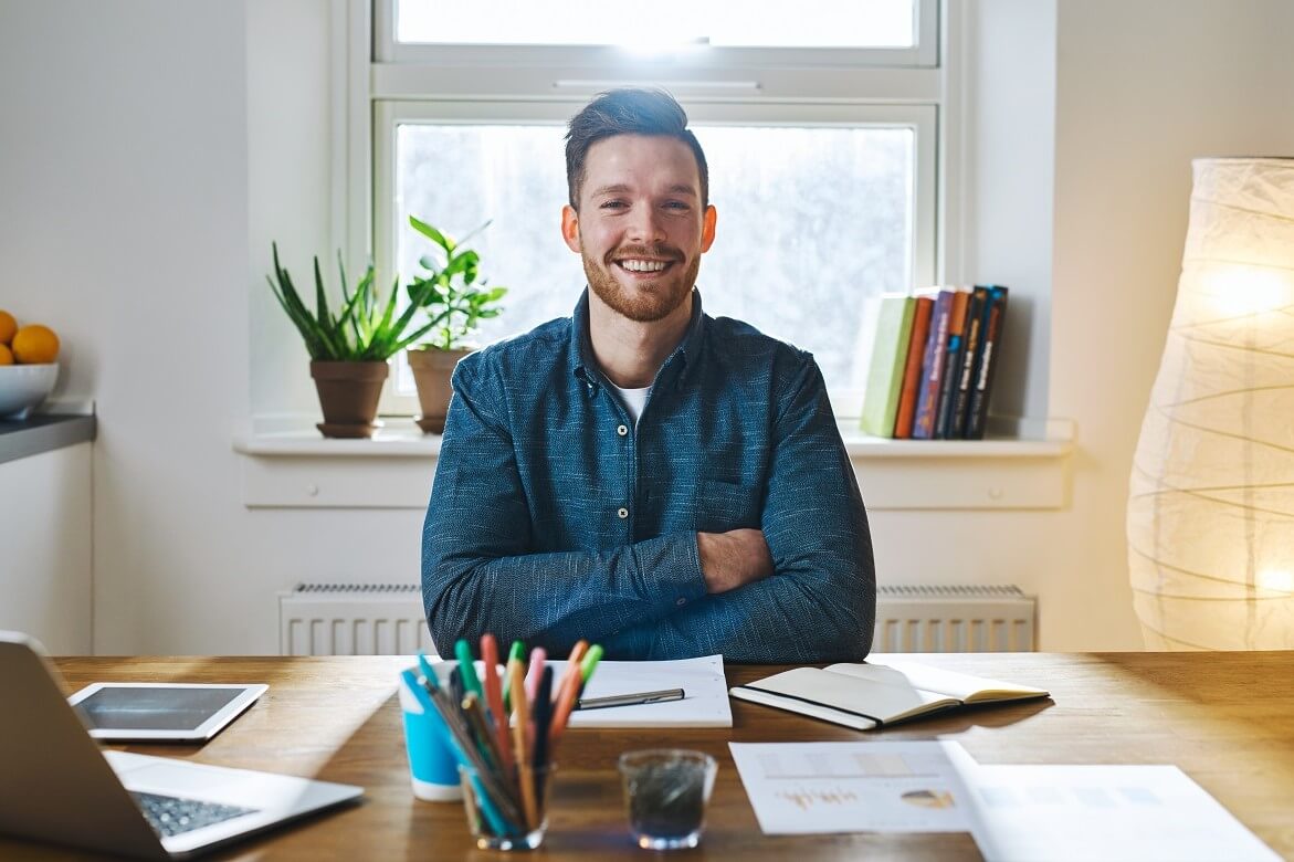 bearded man at home desk with folded arms