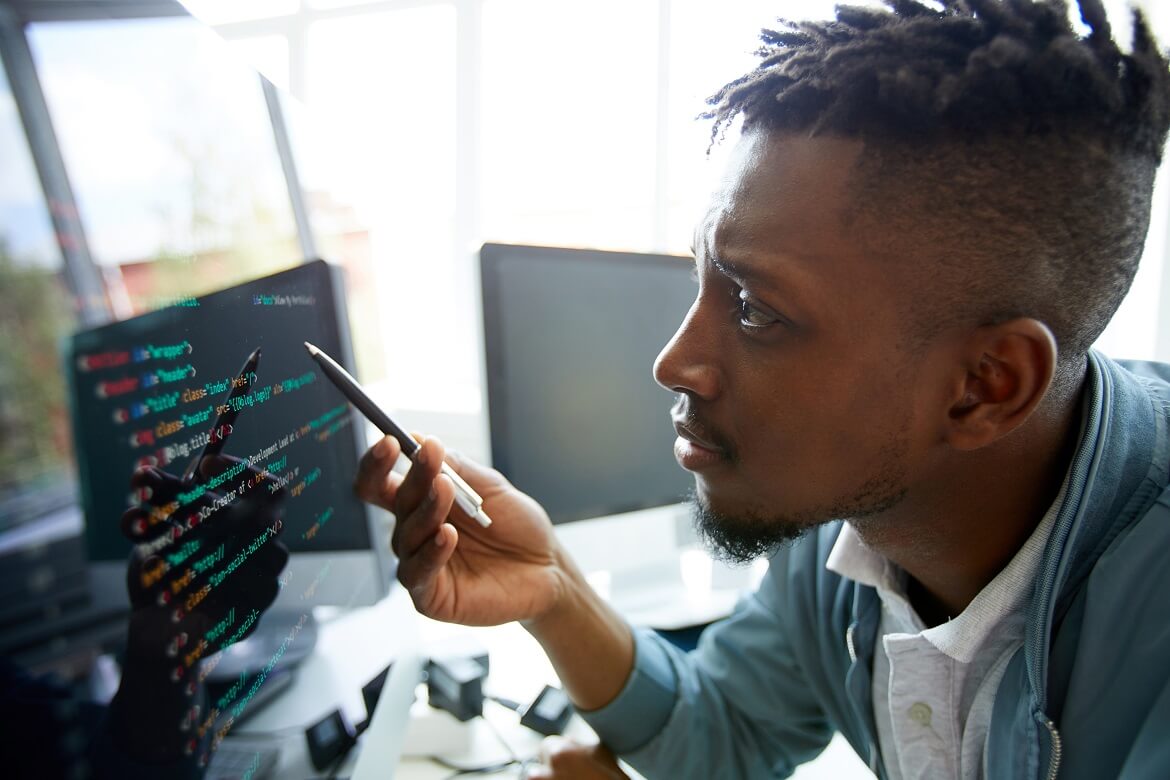 male office worker at desktop computer reading coding