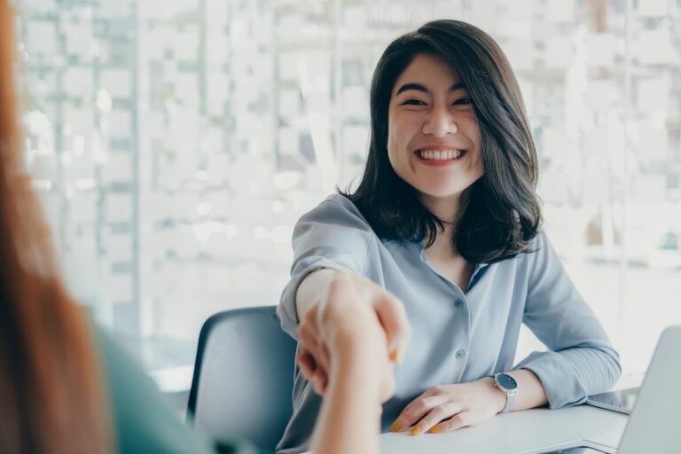 smiling happy businesswoman shaking hand greeting female partner