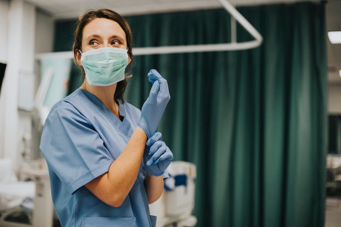 A nurse putting on gloves and wearing a mask