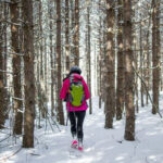 A woman hiking through the woods during the winter
