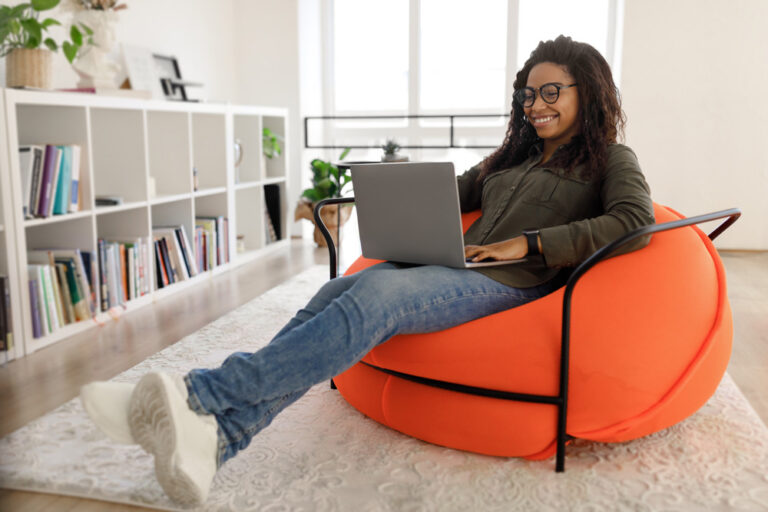 Young woman using laptop while sitting on an orange chair