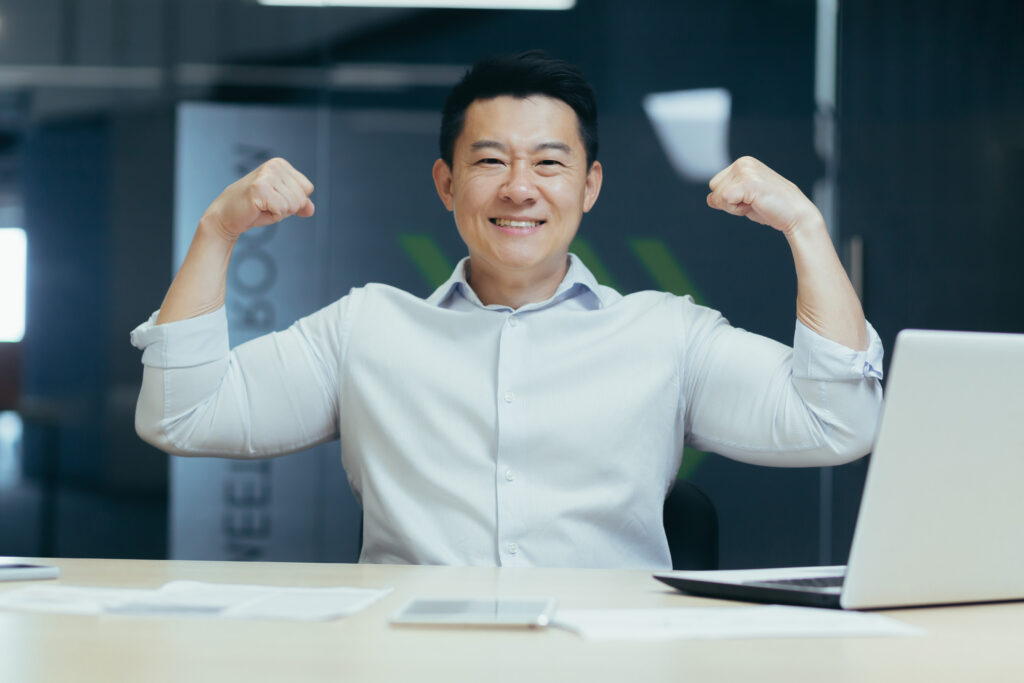 A successful and handsome young Asian business man shows with his hands that he is strong in an office