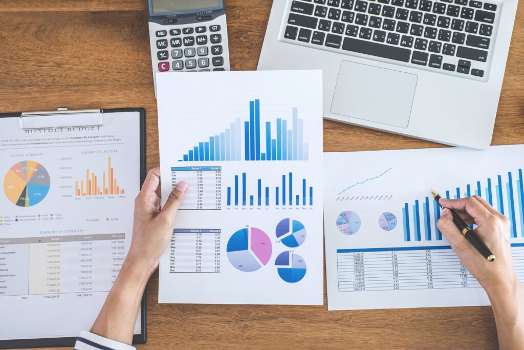 Shot from above of a disembodied hand holding a sheet with charts and graphs and holding a pen with their other hand